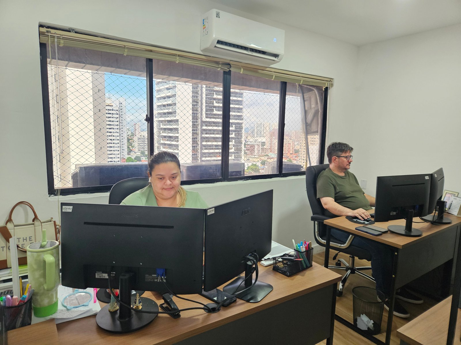 Profissionais GHM em frente a monitores, com vista externa pela janela.